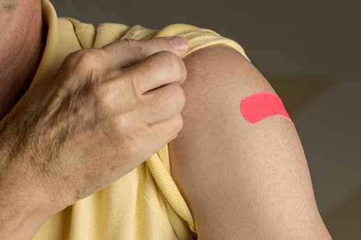 person holding up shirt sleeve to show bandage