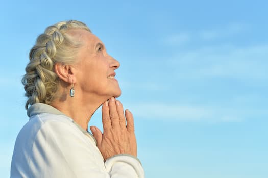 person looking to the sky with their hands together